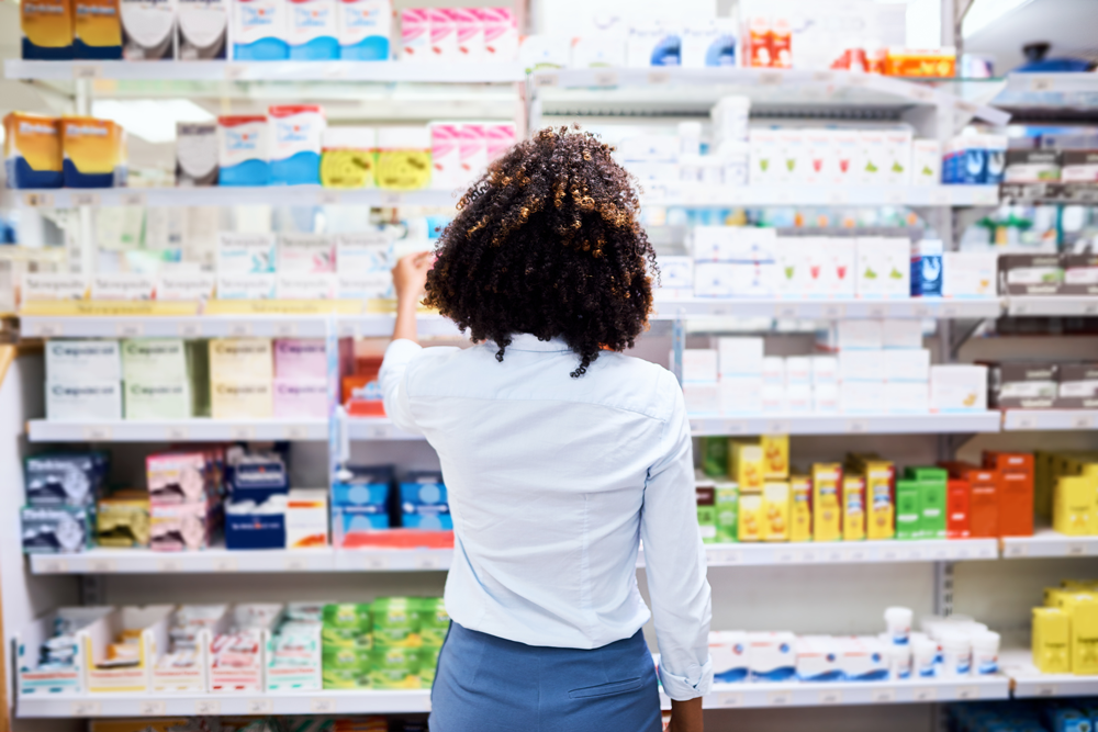 A professional examining nonprescription drug options in a pharmacy, highlighting accessibility and organization of over-the-counter medications.